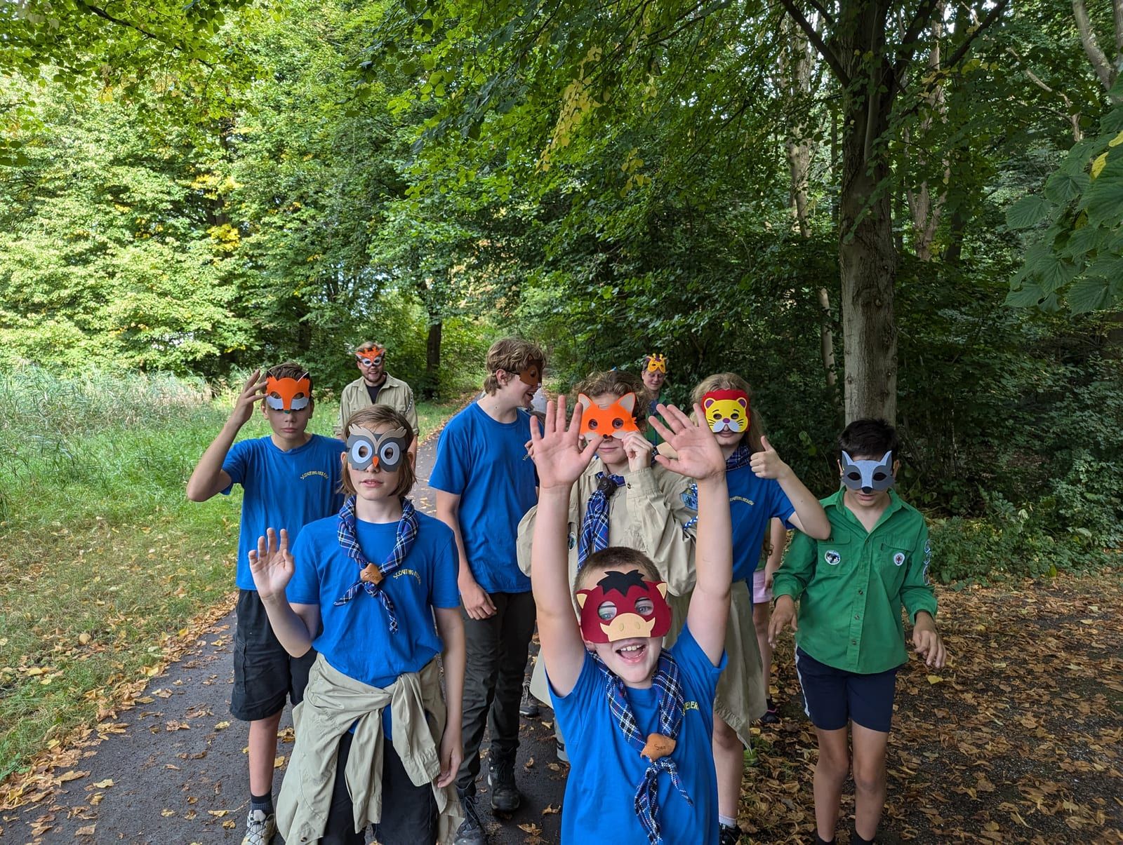 Welpen met zelfgemaakte maskers zwaaien op een bospad